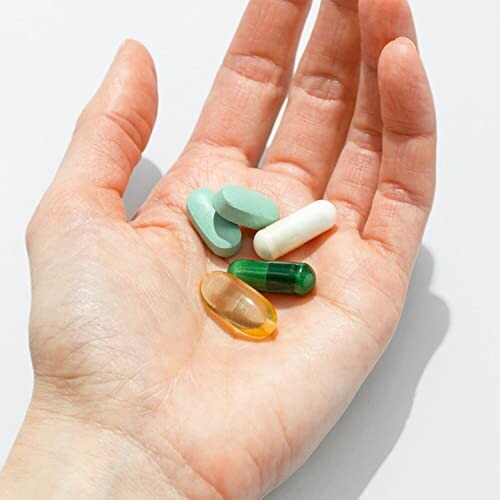 Hand holding assorted pills and capsules.